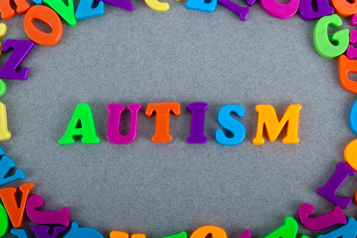 word autism in bright words with all the letters of the alphabet around it