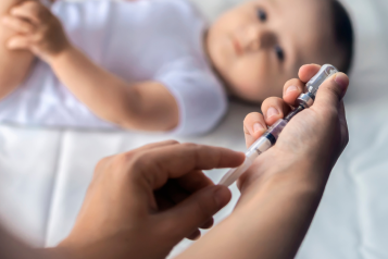 baby with someone using a syringe for World Immunisations Day